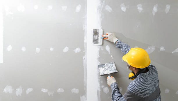 interior decoration construction furniture builtin.Plasterer in working uniform plastering the wall indoors.